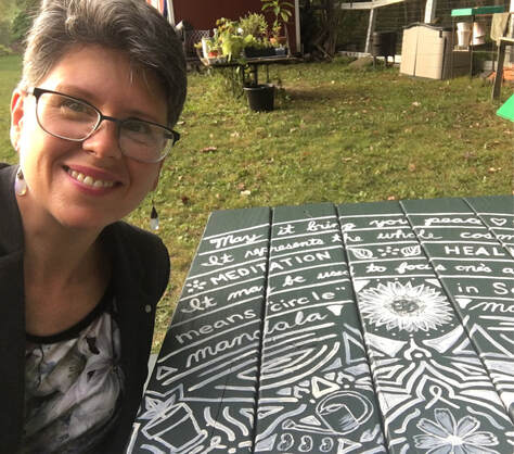 April Castoldi, artist, posing by hand-painted garden mandala table at Green Chimneys, Brewster, New York